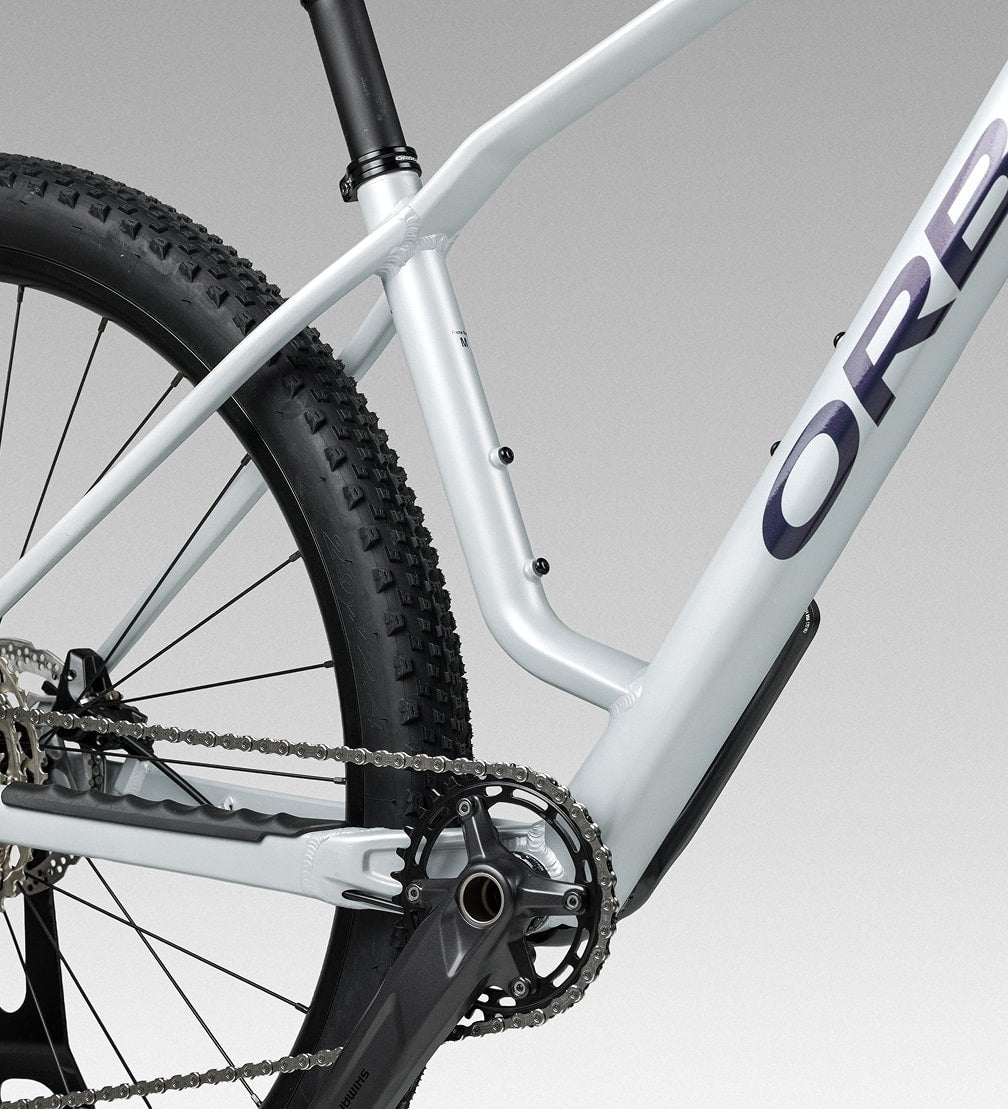 Close-up of a bicycle with asilver frame and black tyres on a gray background