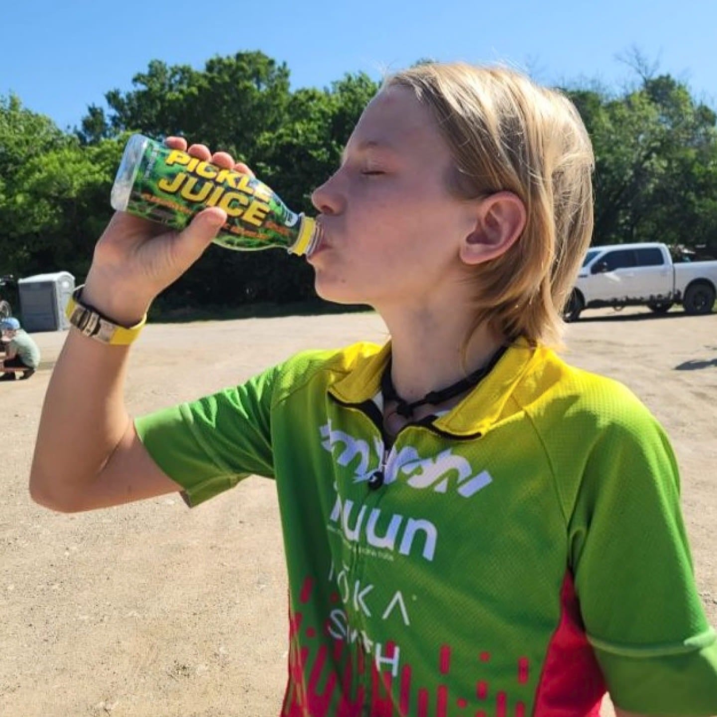 A kid drinking Pickle Juice outdoors