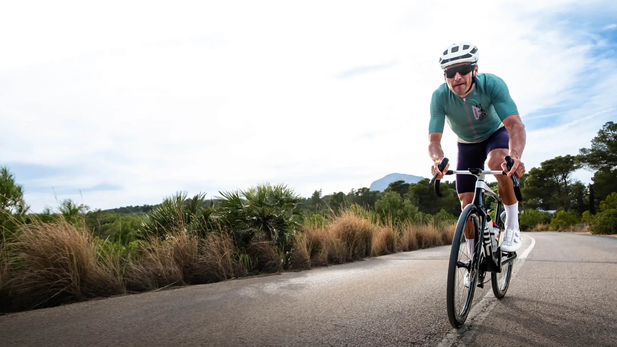 Person cycling on a road with a scenic background