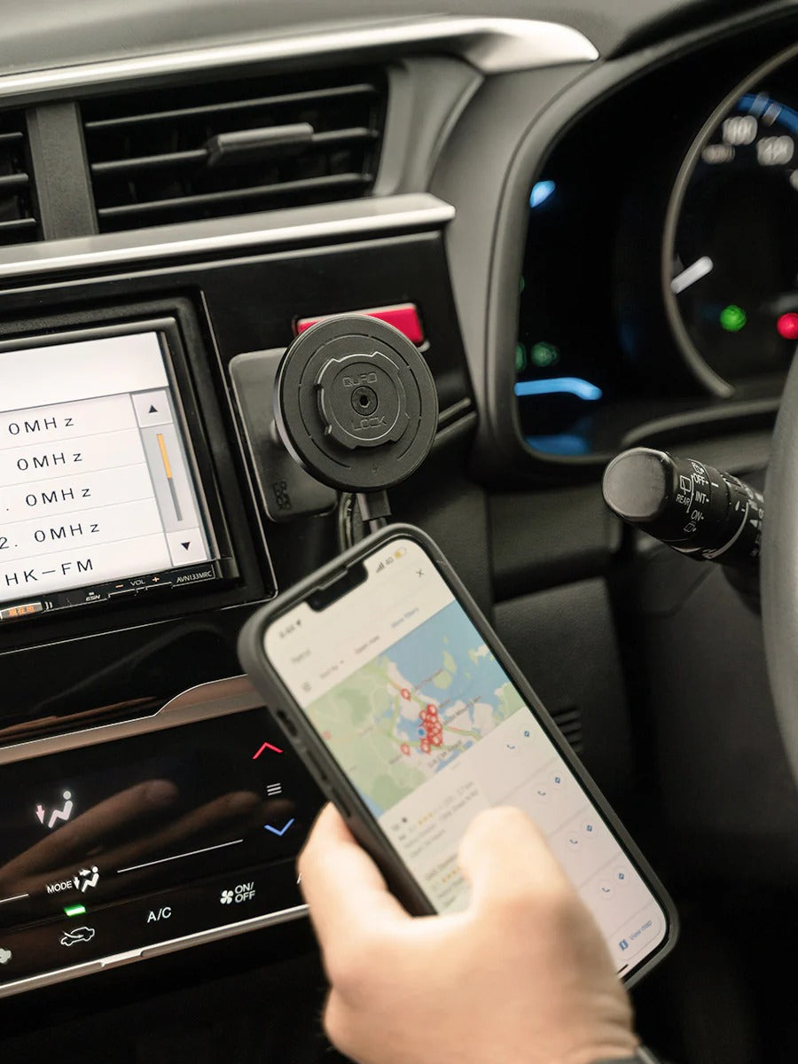 Person using a smartphone with a map app in a car, mounted Quad Lock phone holder visible