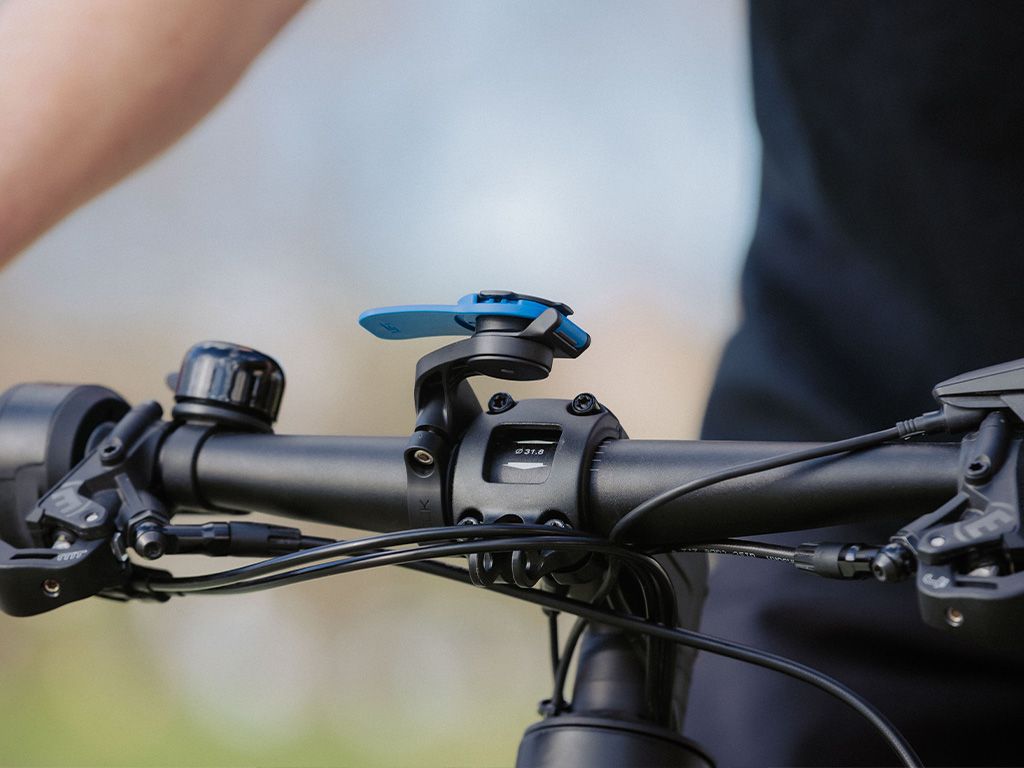 Close-up of a bicycle handlebar with a phone mount on a blurred background