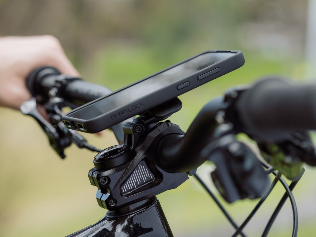 Phone mounted on a bicycle handlebar with the Quad Lock Phone Case and Mount with a blurred natural background