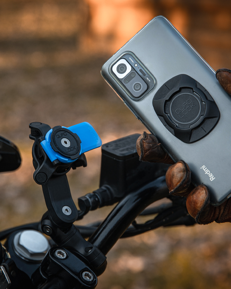 Phone about to be mounted on a bike handlebar with a blurred natural background