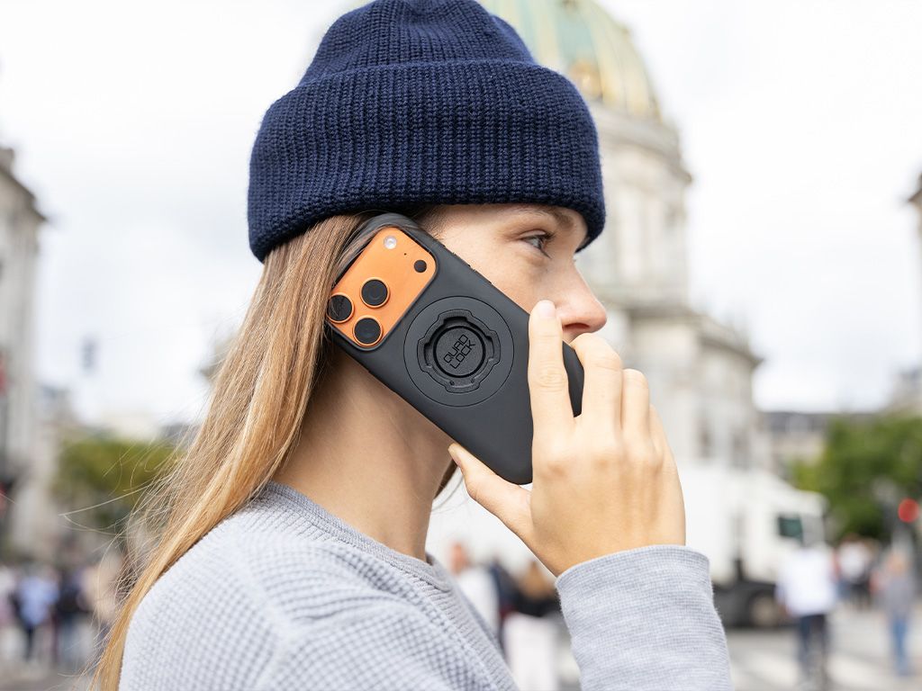 Person using a phone with a Quad Lock Phone case on a city street