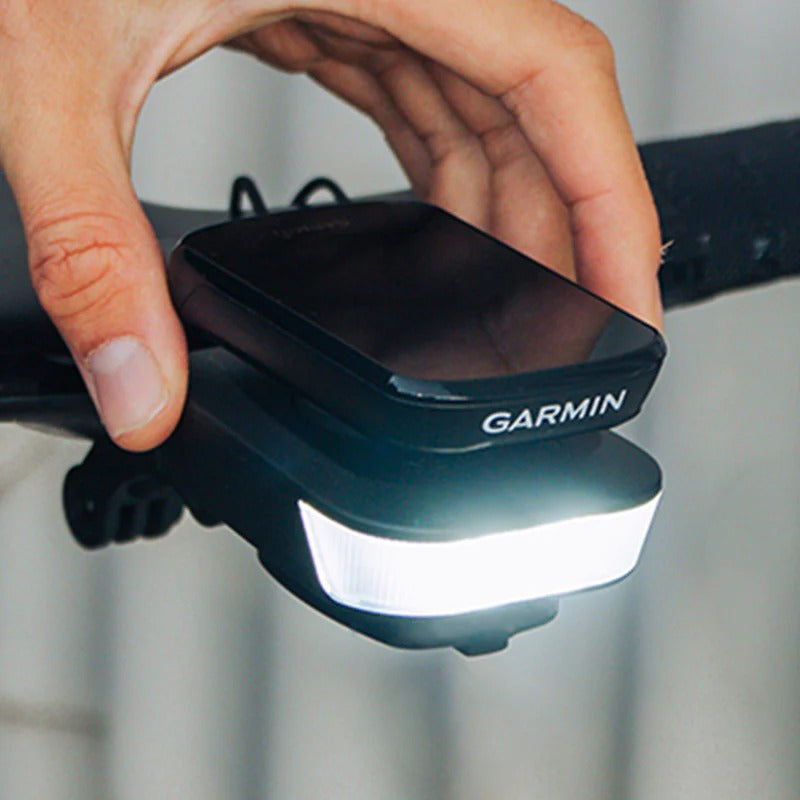 A hand attaching a Garmin computer to the top of the Ravemen FR500 Front Bicycle Light on a road bike with a blurred background