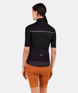 Person wearing a black cycling jersey, black vest and orange shorts on a white background