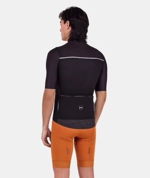 Person wearing a black cycling jersey, black vest and orange shorts on a white background