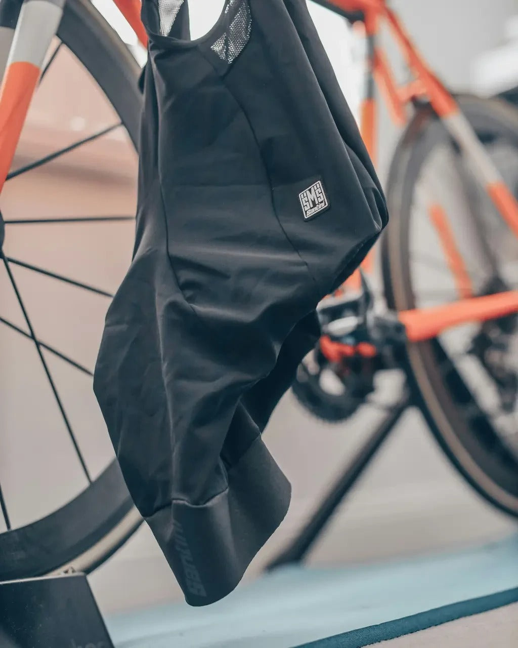 A pair of Santini Cycling Bibshorts hanging on the handlebar of a bike which is blurred in the background