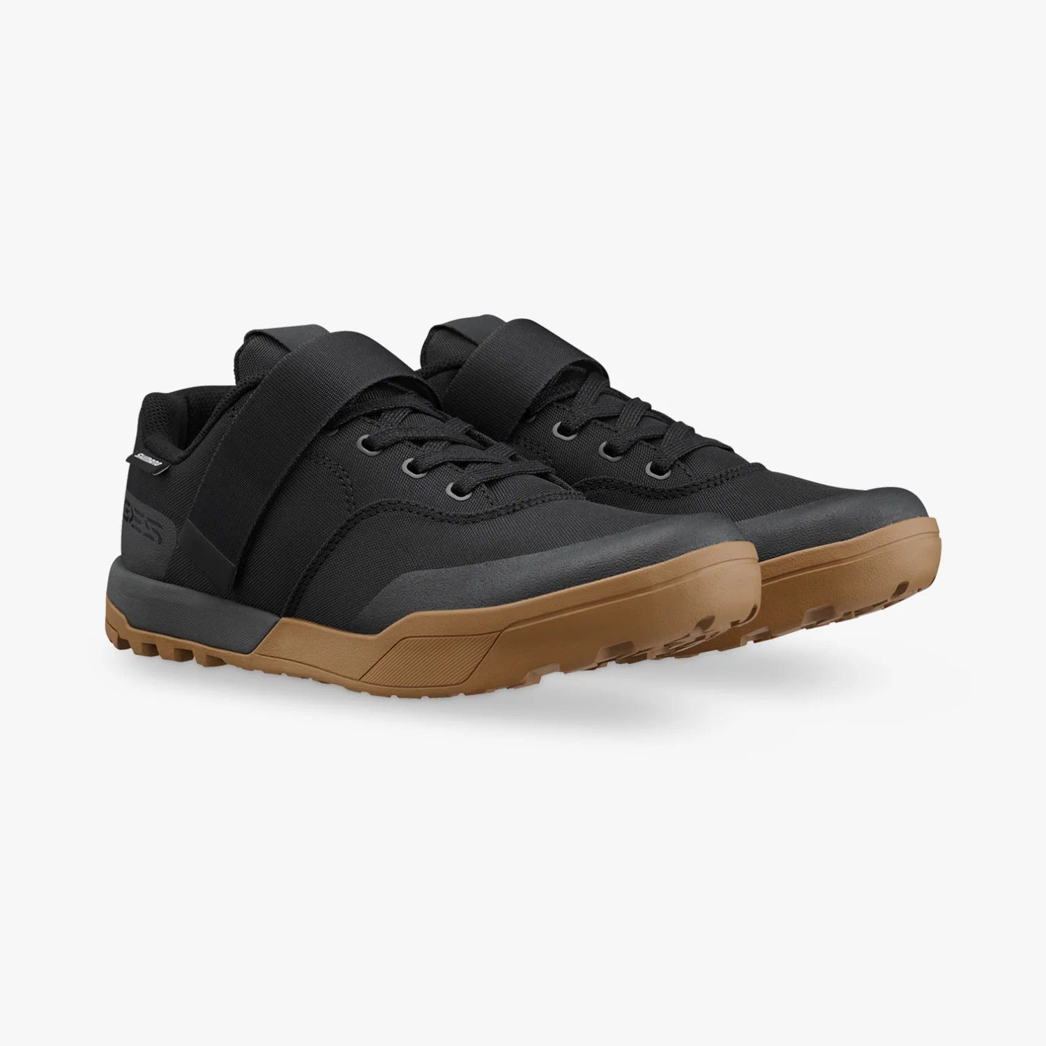 A pair of black mountain bike shoes with brown soles against a white background