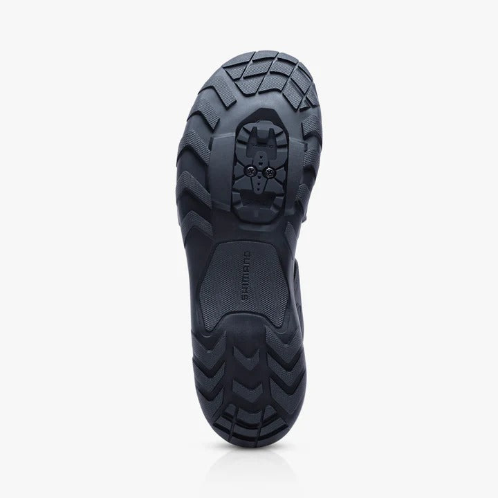 Black cycling shoe sole with tread pattern and cleat bolts on a white background