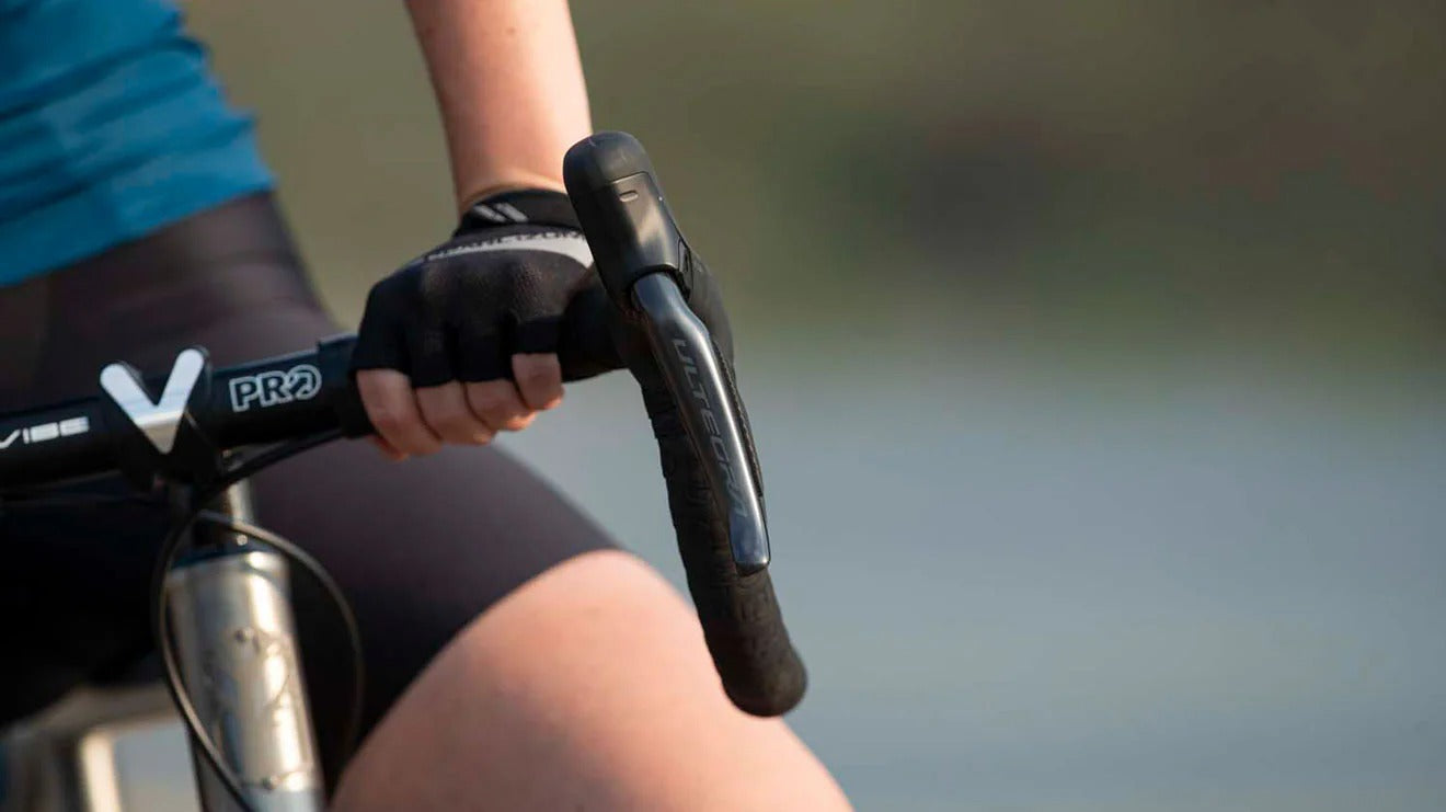 Close-up of a person holding bicycle handlebars with a blurred natural background