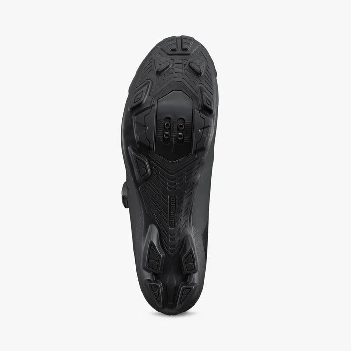 Black cycling shoe sole with tread pattern showing cleat bolts on a white background