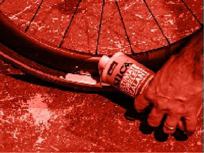 Hand holding the Silca Ultimate Tyre Sealant and inserting it into a tyre with a red filter applied