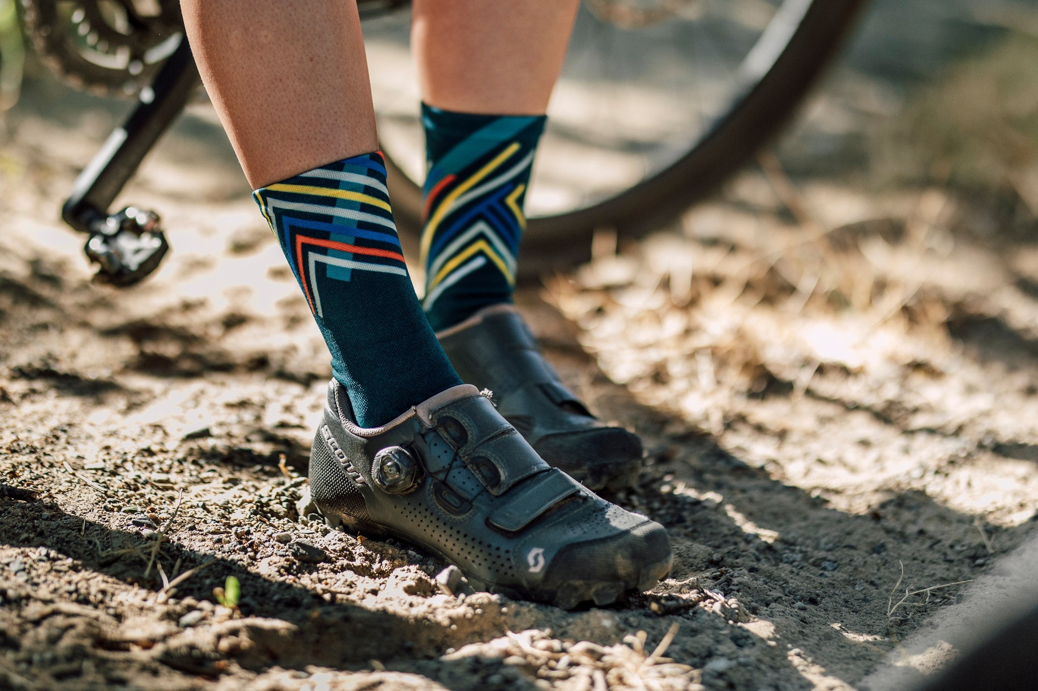 A picture of someone wearing the Sox Performance Teal Cycling Socks with gravel shoes on