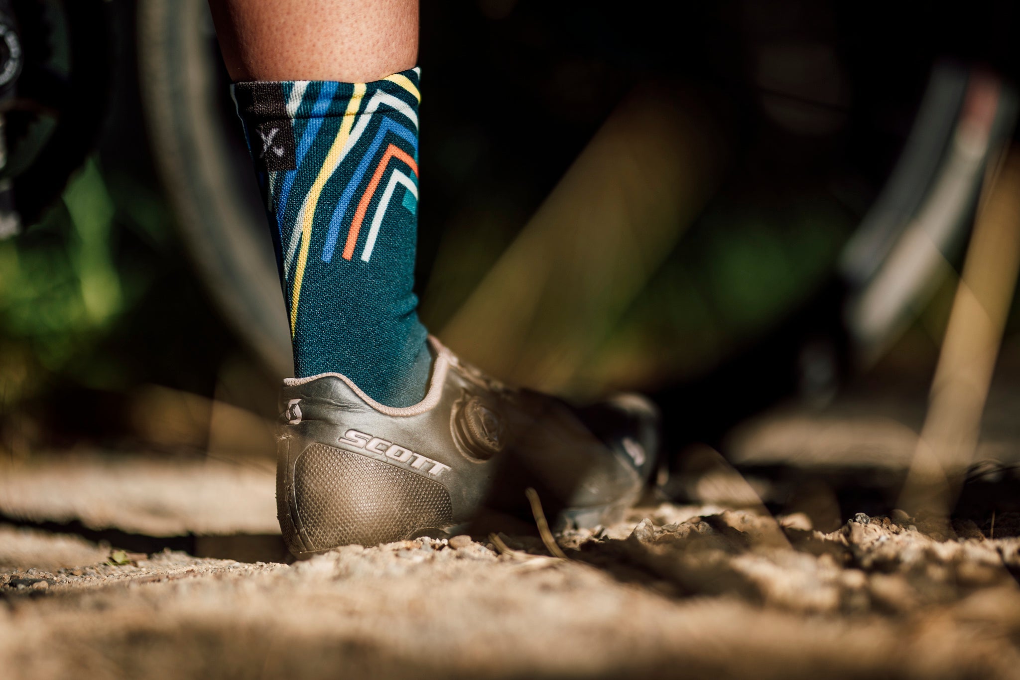 A picture of someone wearing the Sox Performance Teal Cycling Socks with gravel shoes on