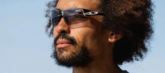 A man wearing light tinted sunglasses with blue sky in the background