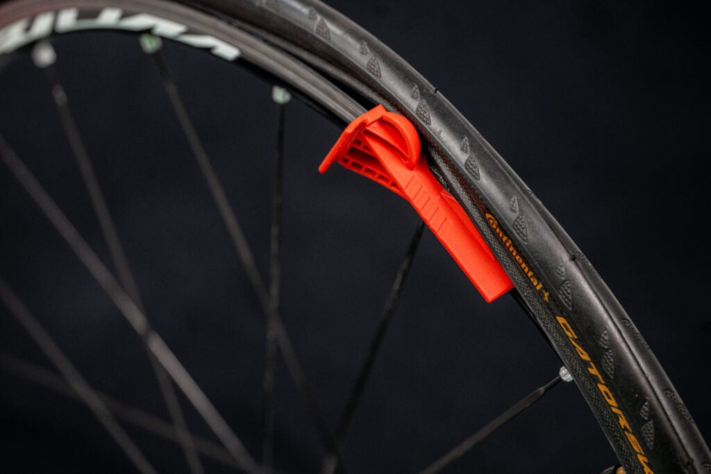 Close-up of a bicycle wheel with a red  tyre levertool on a dark background