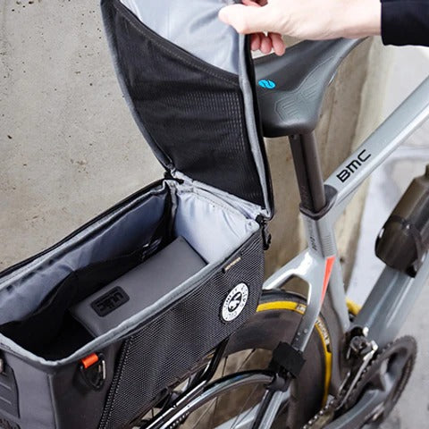 Bicycle with a black pannier bag attached, held open by a hand.