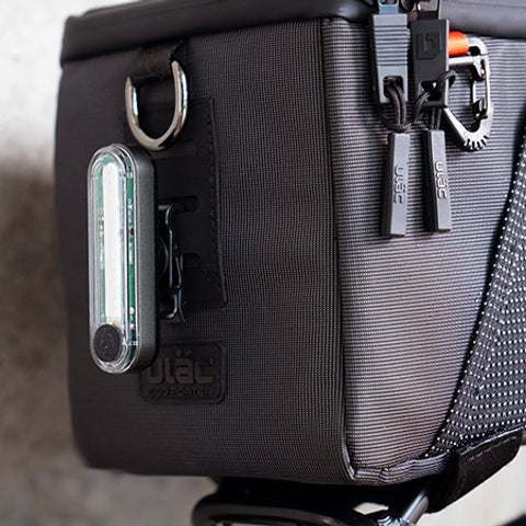 Black ULAC Bicycle Pannier Bag with rear light and lock on zips against a blurred background