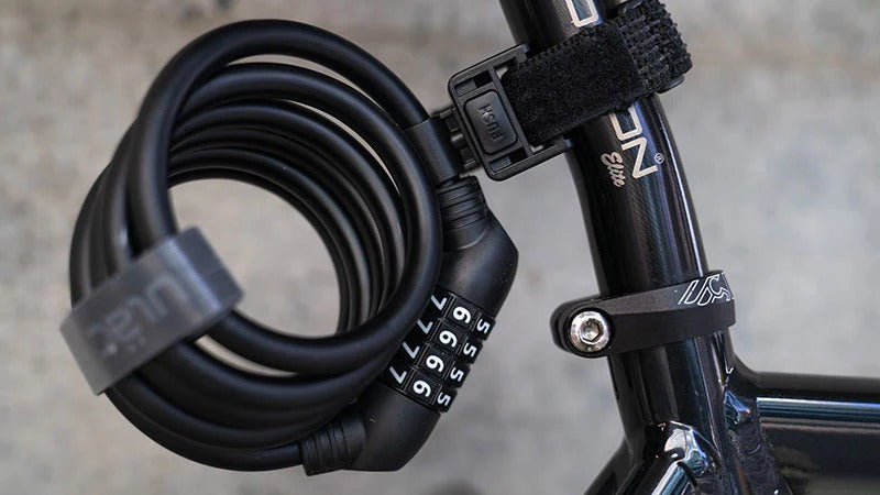 A close up of a bicycle cable lock attached to a bicycle seatpost