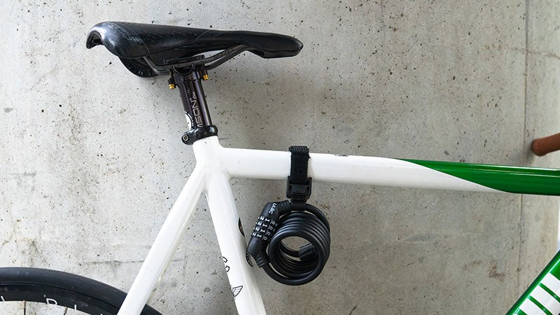 Bicycle with a lock attached to the top tube, leaning against a concrete wall