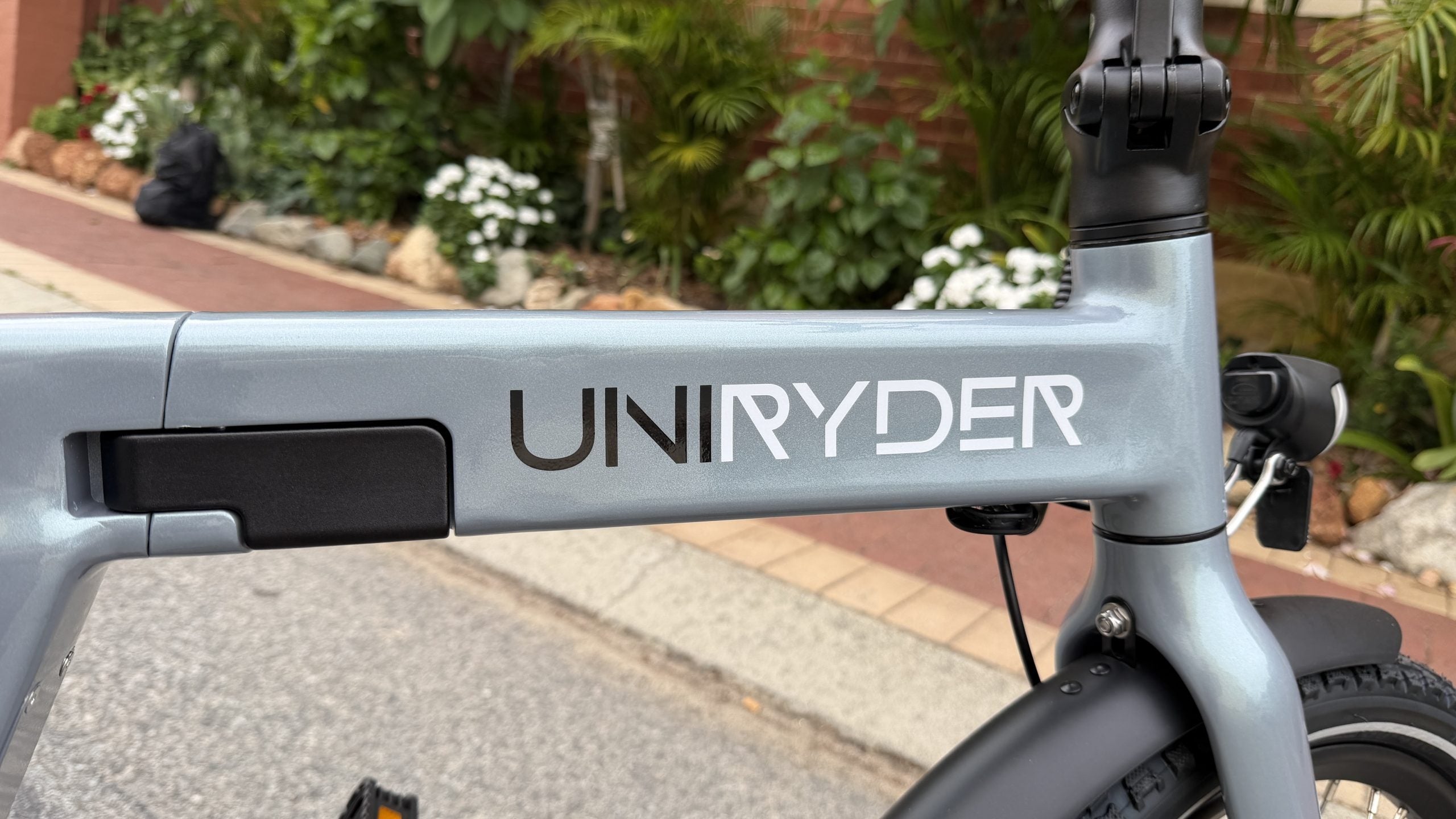 Gray electric bike with 'UNIRYDER' branding on a sidewalk.