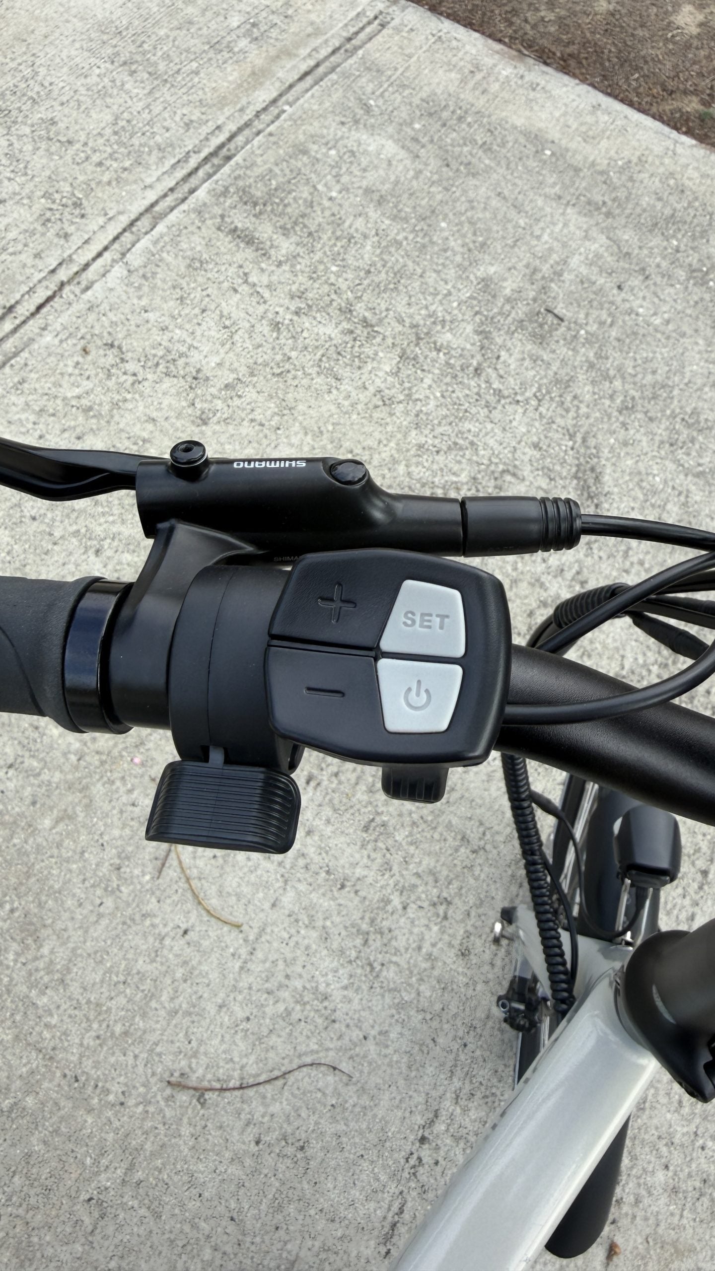 Close-up of an electric bicycle handlebar controls on a concrete surface