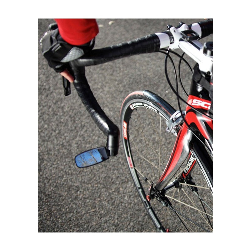 Close-up of a road bike with a red frame and a mirror fitted to the drop bar on a road