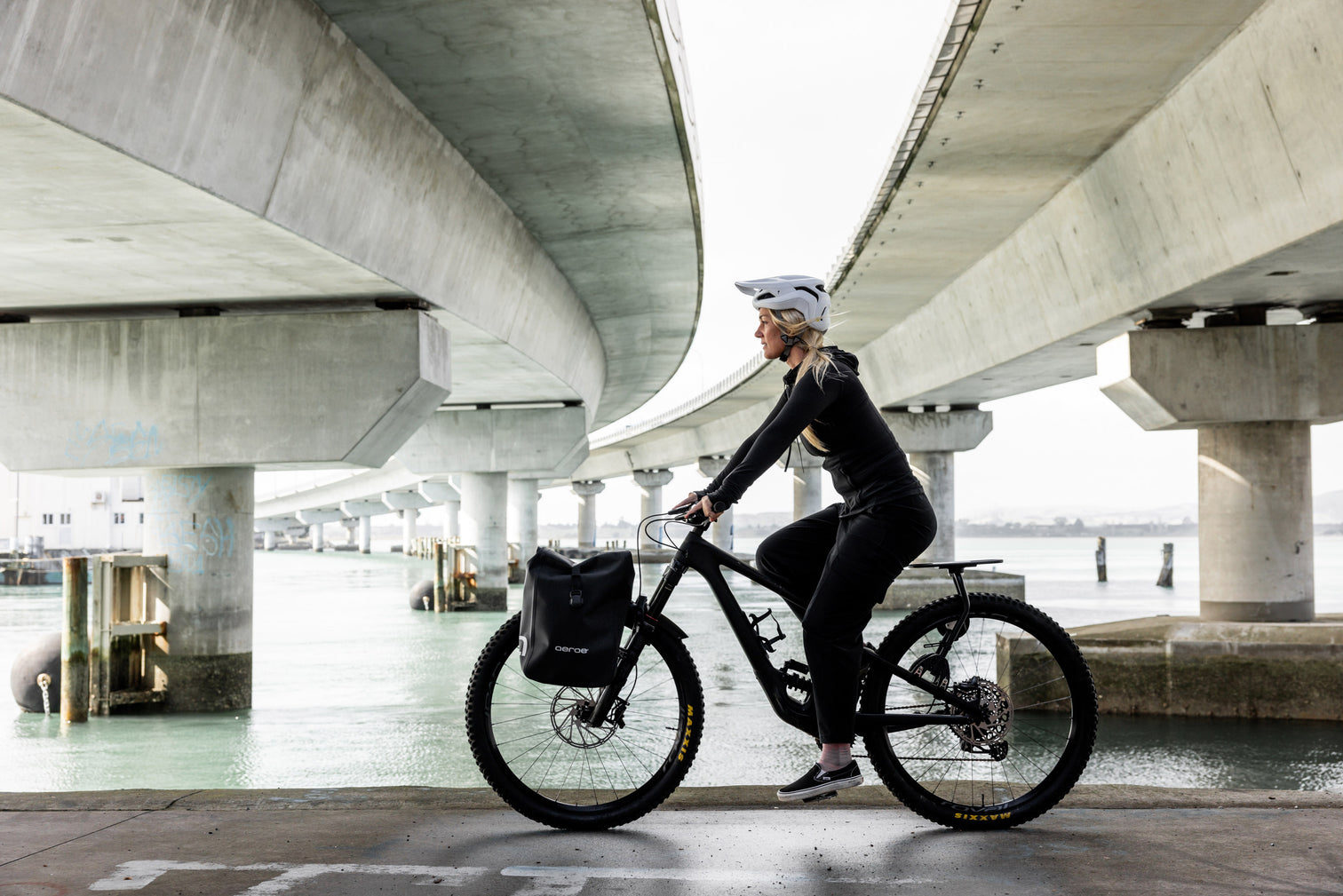 A picture of a lady riding a bike with the Aeroe Front Bike Rack and bags attached to their bike