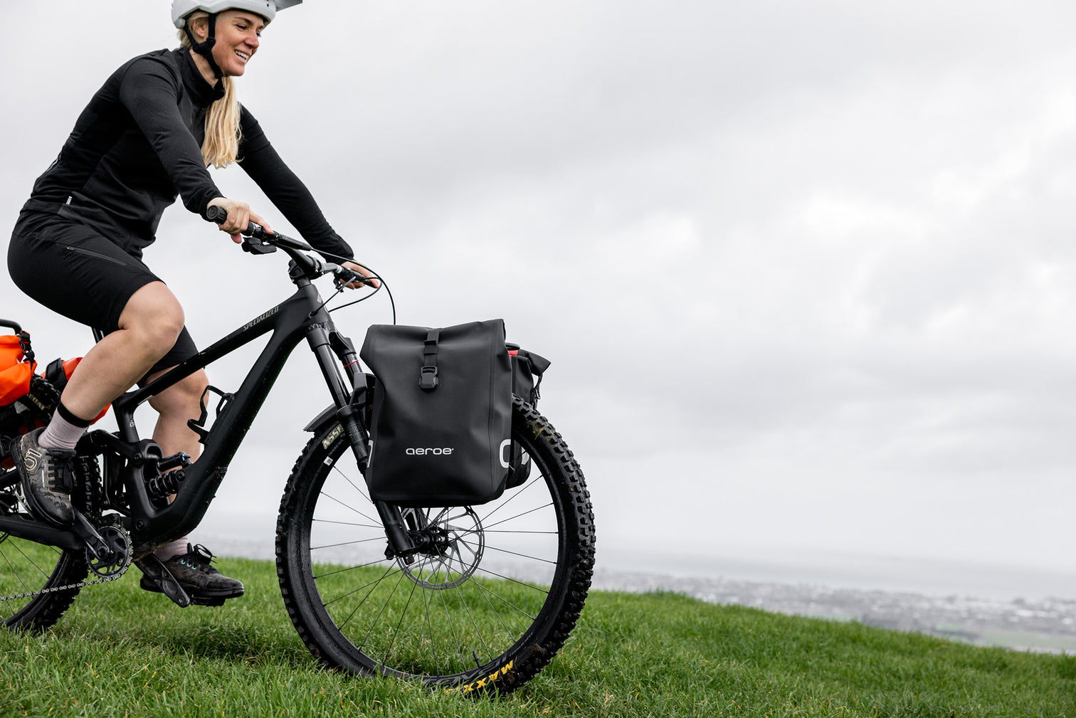 A picture of a lady riding a mountain bike with the Aeroe Front Bike Rack attached to her bike with bags