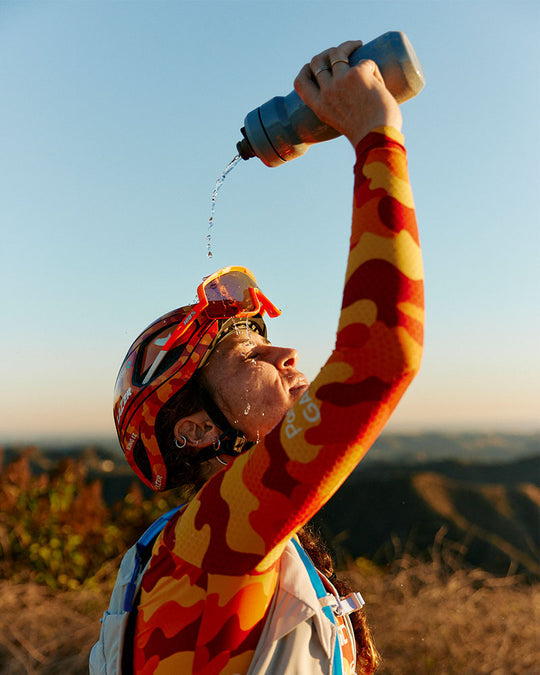 A picture of the lady mountain biker pouring water over her head from a Camelbak Podium water bottle