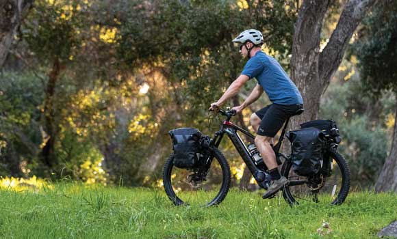 A person riding a mountain bike with the Topeak MTS Trunk Bags attached to the bike