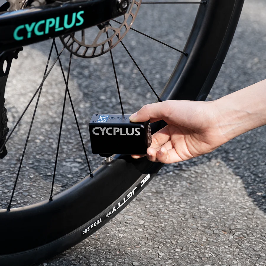 Person using a CYCPLUS electric bike pump on a bicycle tre