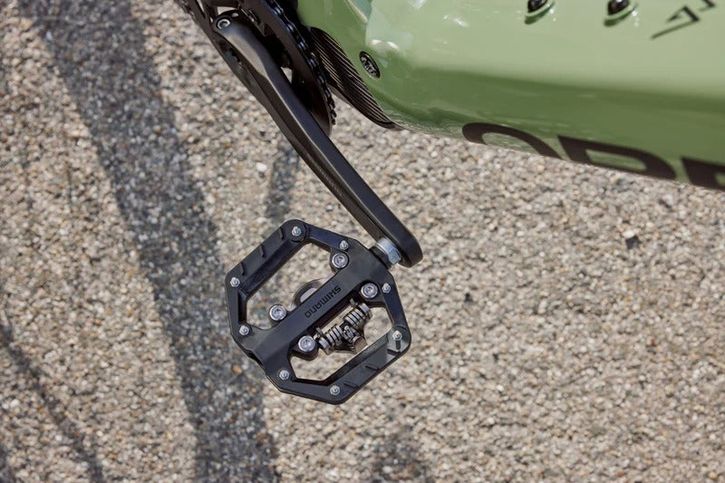 Close-up of a bicycle pedal on a mountain bike with a gravel road in the background