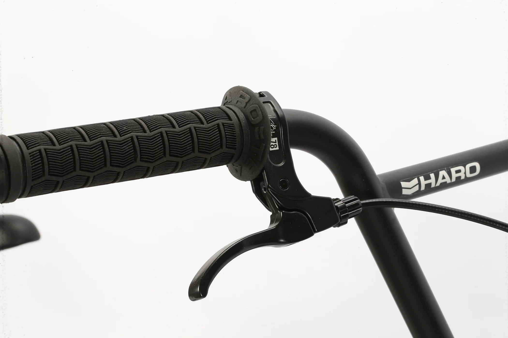 Close-up of a Haro BMX bicycle handlebar with black grips and visible brand logo on a white background