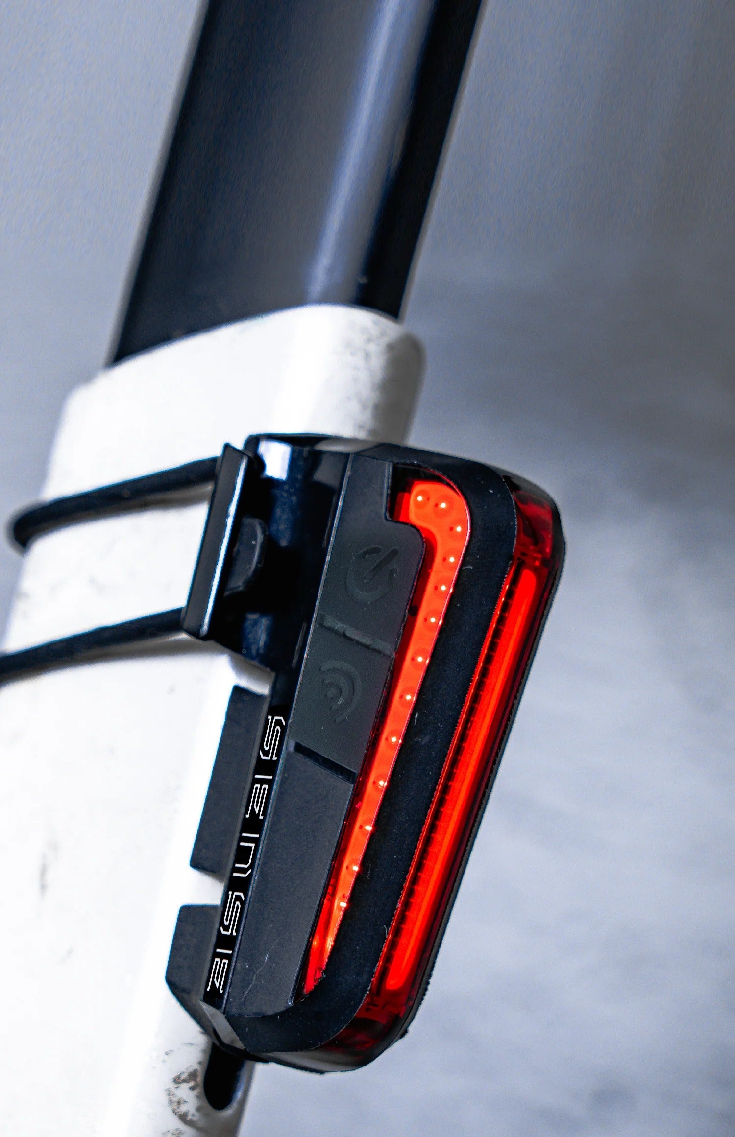 Bicycle tail light attached to a bike frame with a blurred background
