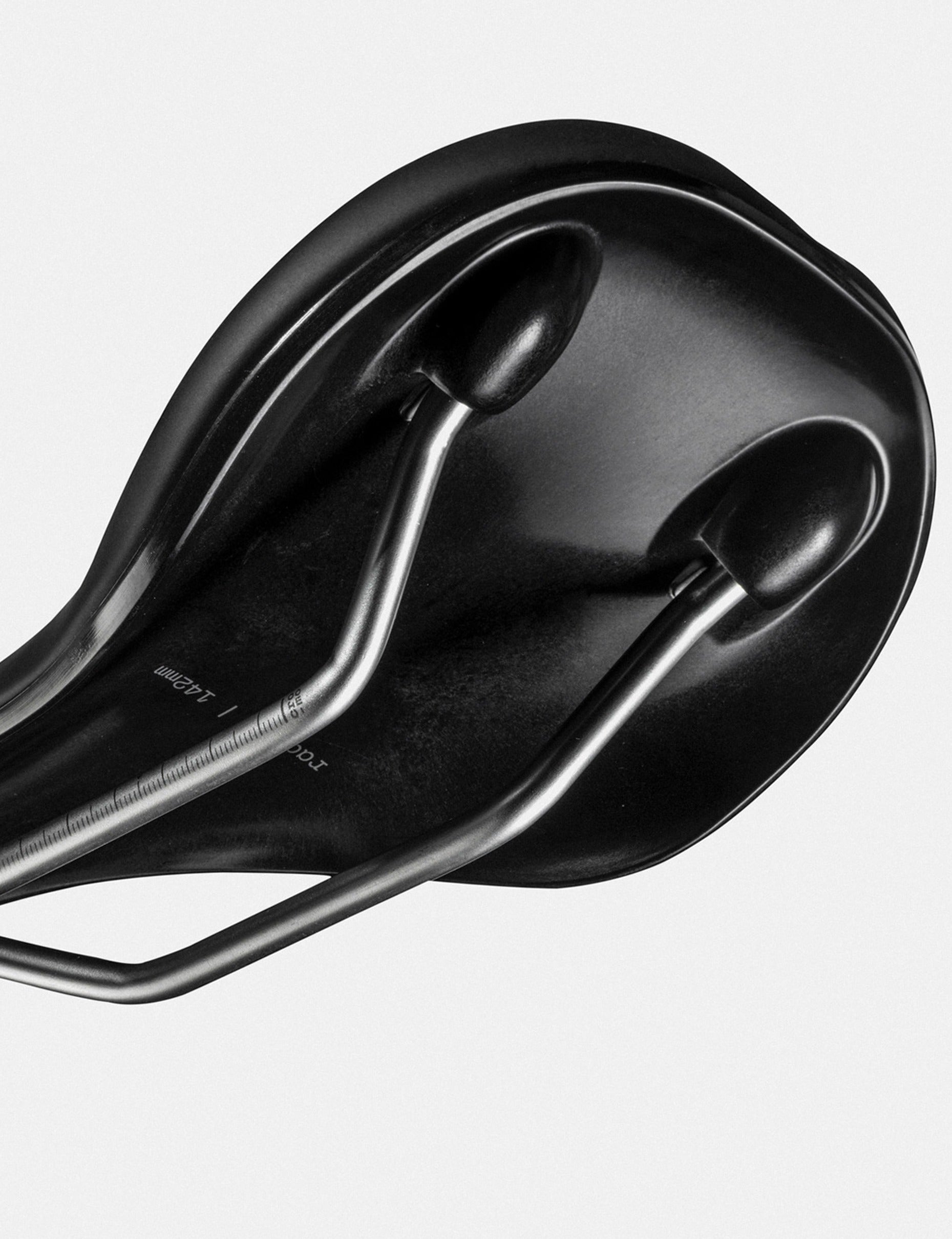 The underneath of a black bicycle saddle on a light gray background