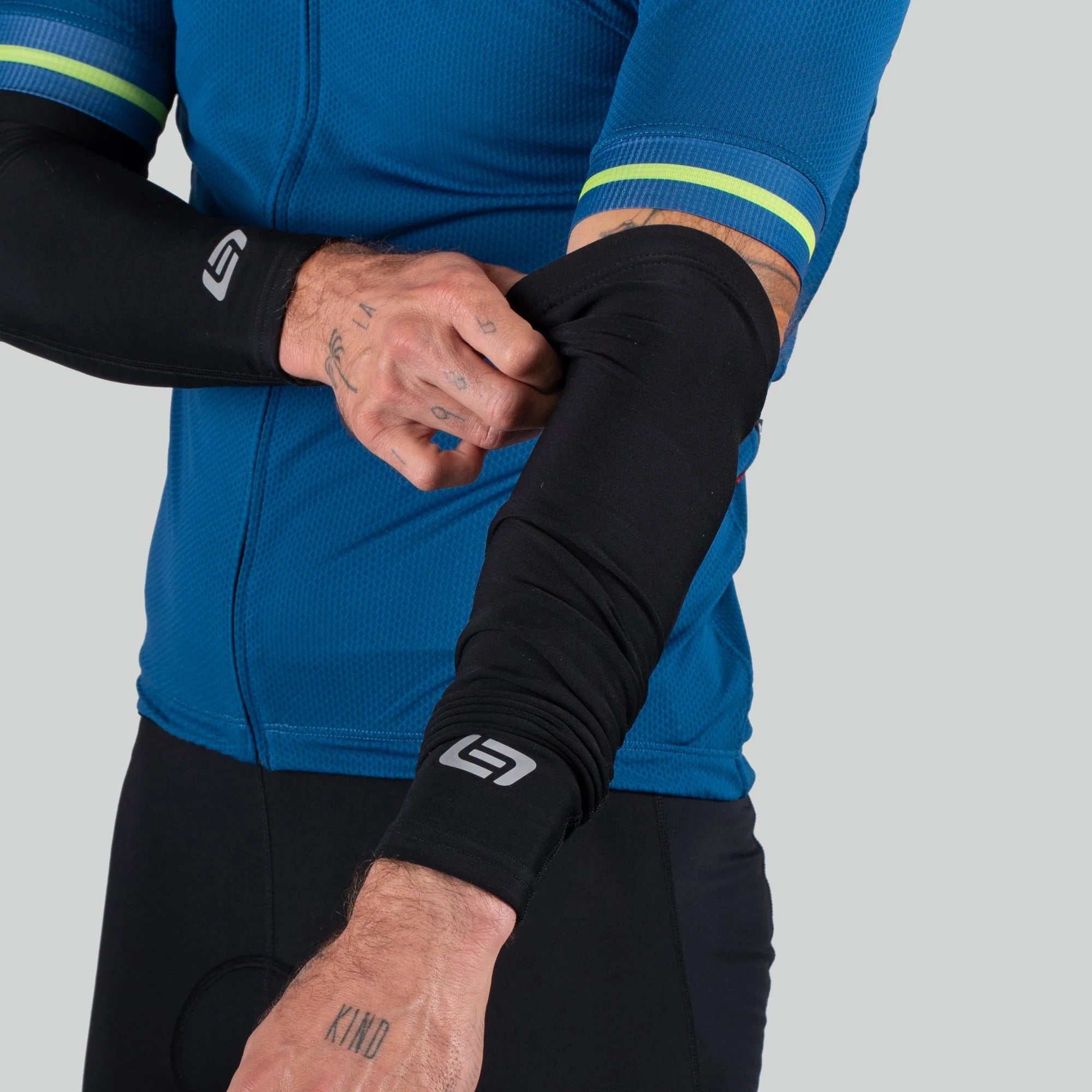 Person wearing a blue cycling outfit with black arm sleeves on a gray background