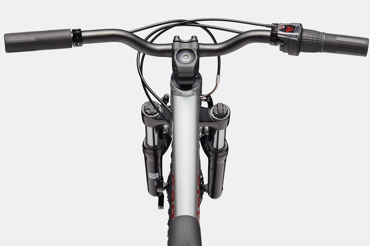Close up of the handlebar and top tube of a silver kids mountain bike on a white background
