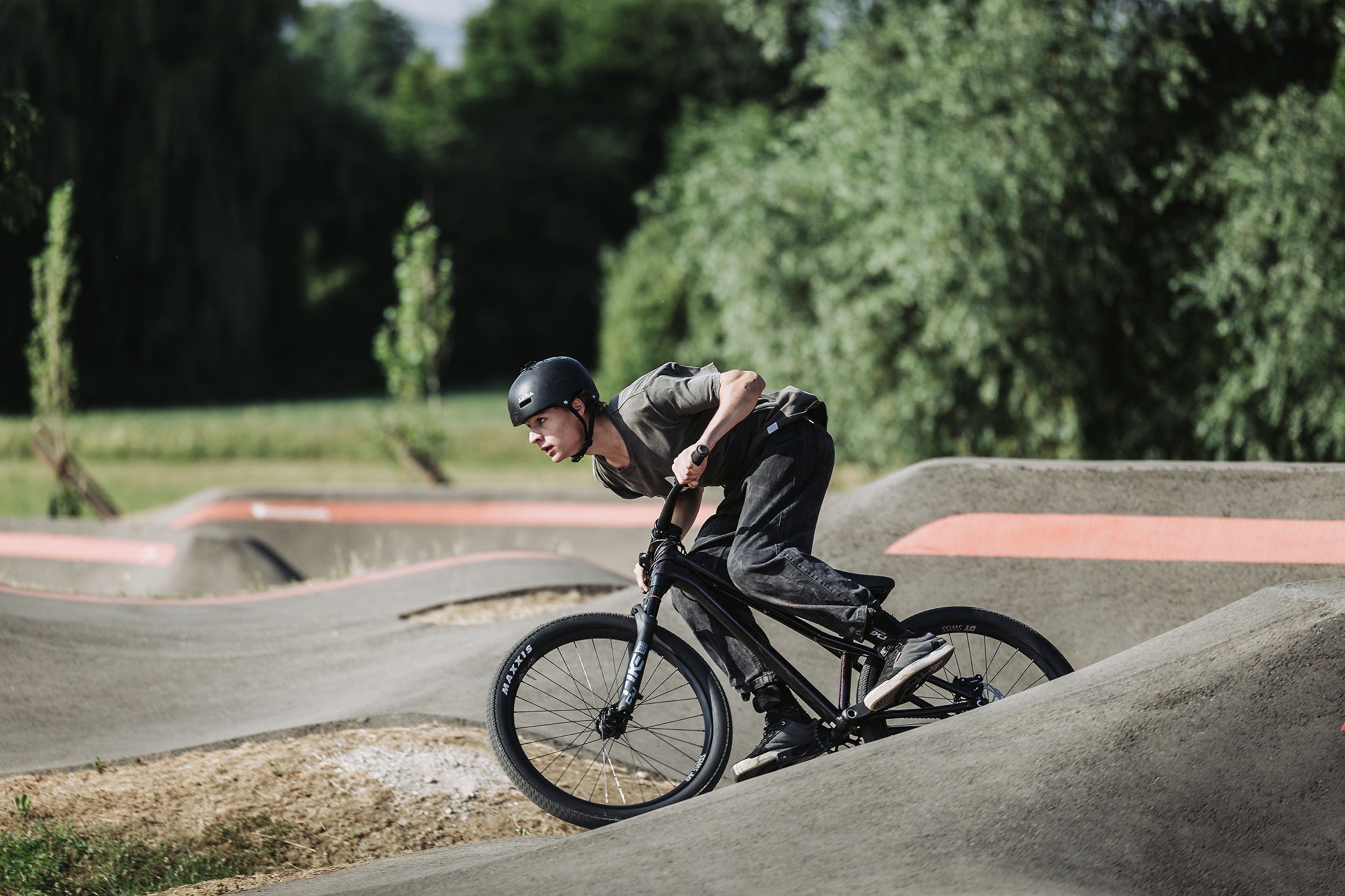 Person riding a bicycle on a concrete track with trees in the background