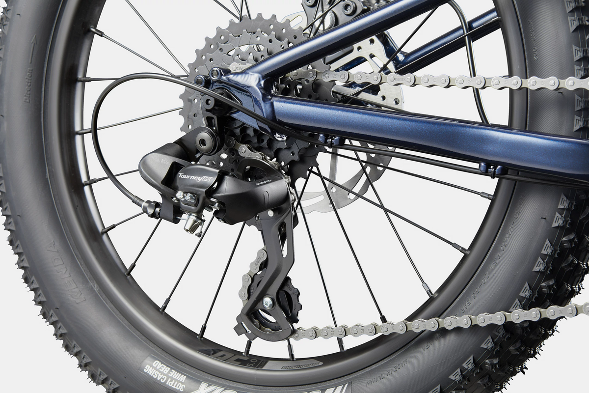 Close up of a rear derailleur on a blue kids mountain bike on a white background