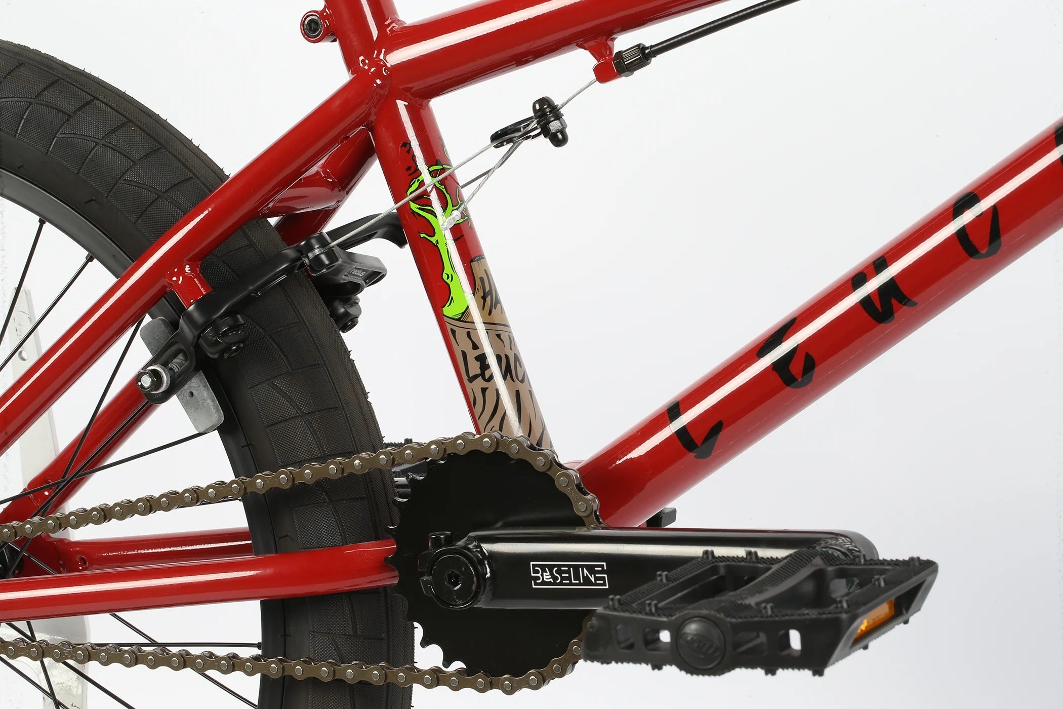 Close-up of a red Haro Leucadia BMX Bike frame with chain and gear system on a white background
