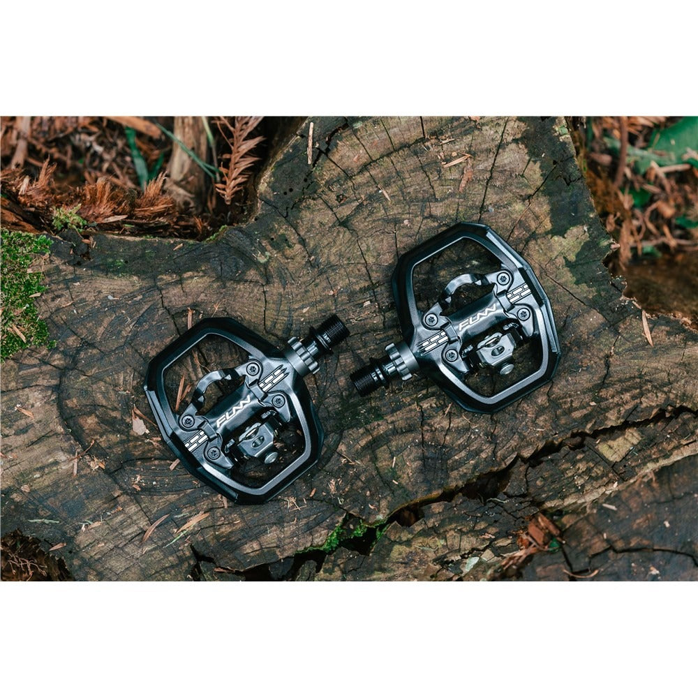 Pair of bicycle pedals on a wooden surface with a natural background
