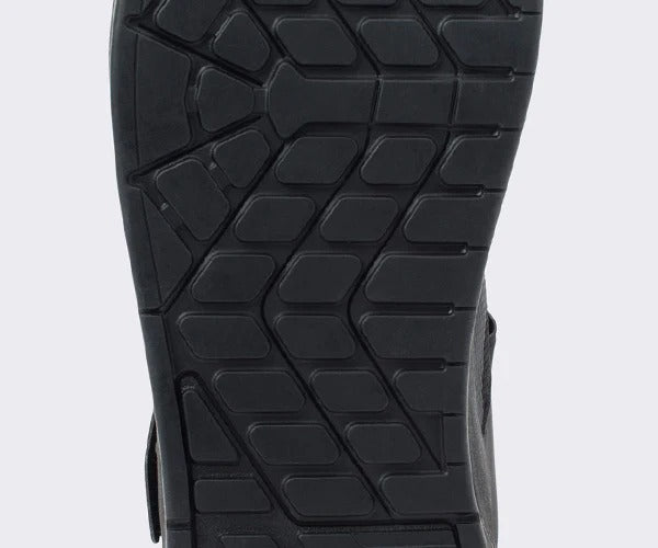 Close-up of a black mountain bike flat shoe sole with textured pattern on a light gray background