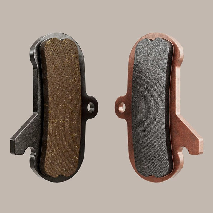A pair of bicycle Disc Brake Pads on a beige background