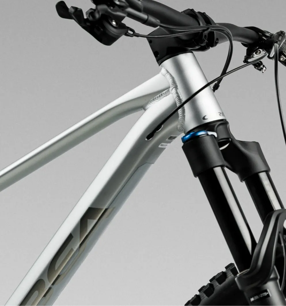 Close-up of a silver mountain bike frame and handlebars on a gray background