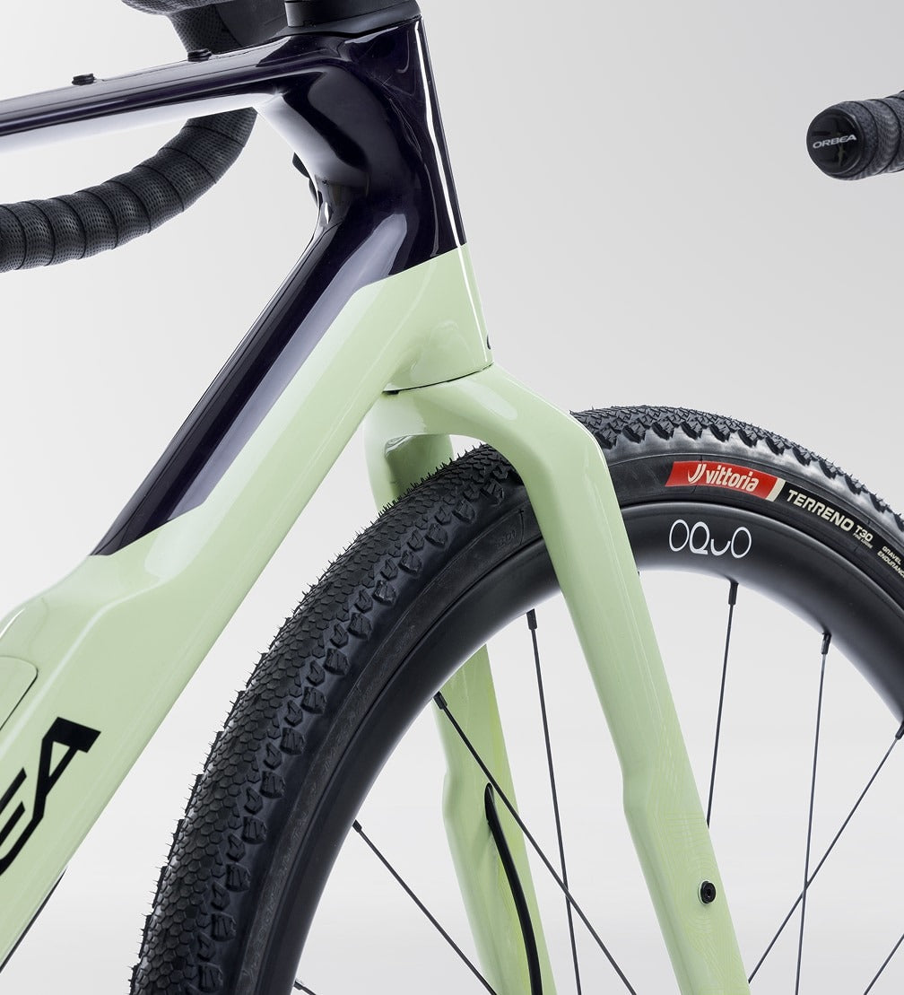 Close-up of a light green Orbea Gravel Bike with black tyres on a white background