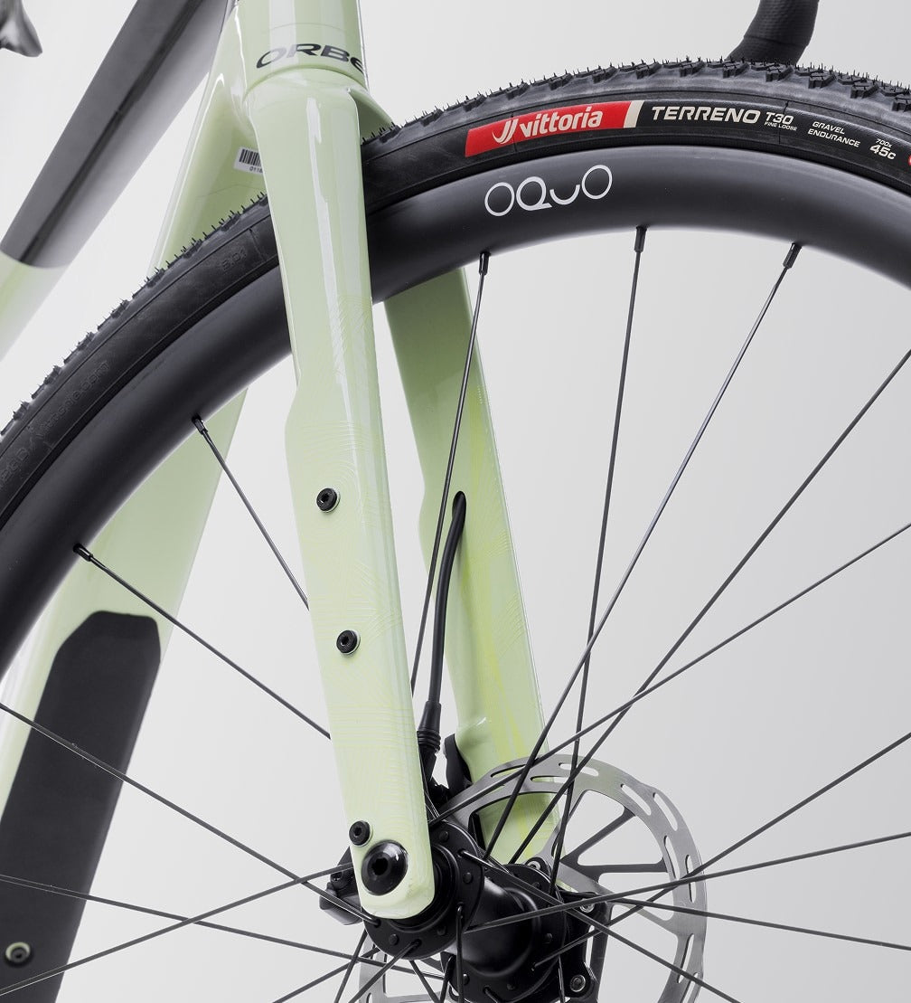Close-up of an Orbea Gravel Bike wheel with a white frame and Vittoria tyre on a gray background