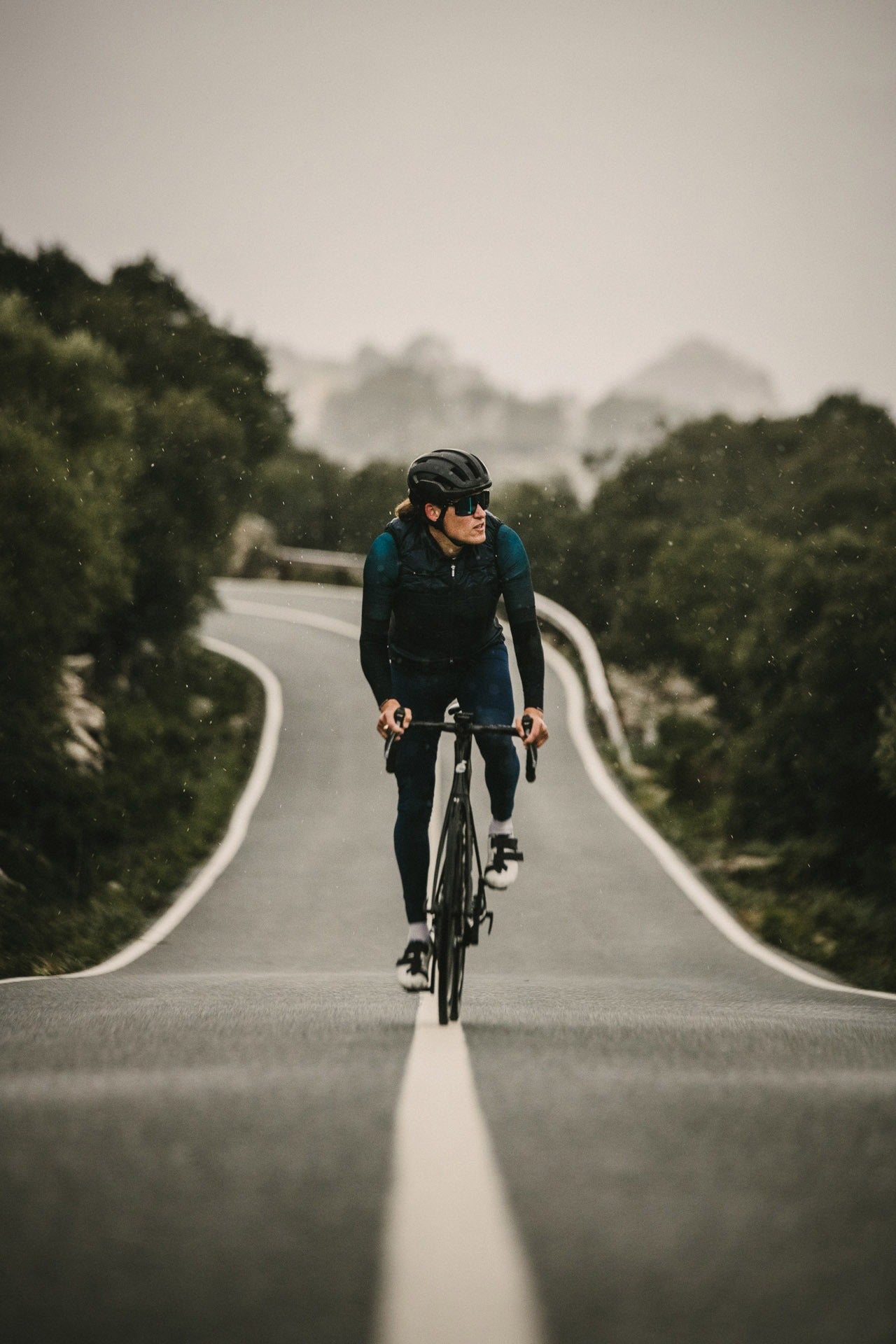 Person cycling on a road surrounded by trees