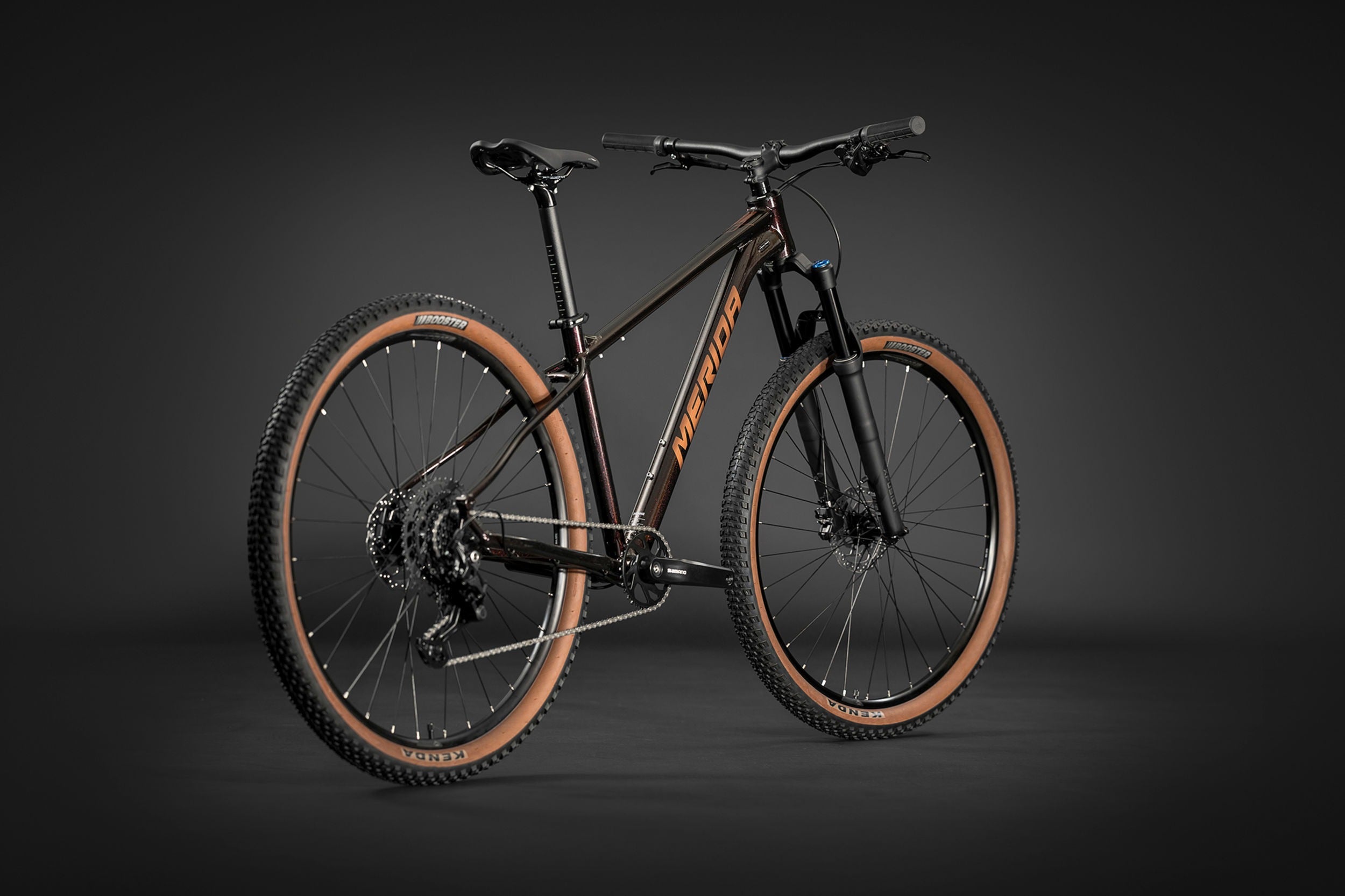 Black Merida mountain bike with brown tyres on a dark background